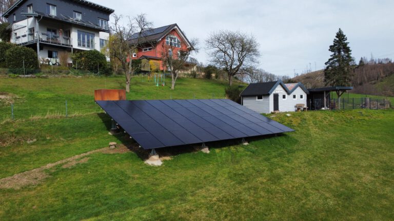 Freistehende Photovoltaikanlage im grünen Garten vor Wohnhäusern zur effizienten, erneuerbaren Energiegewinnung