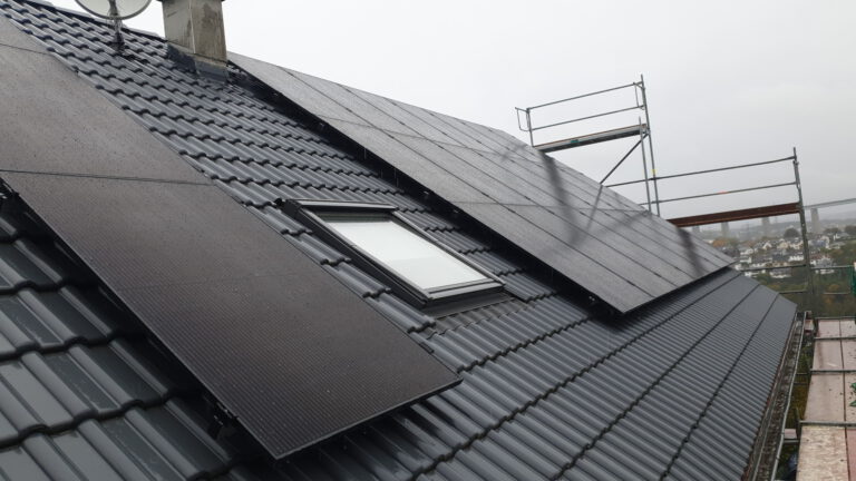 Integrierte schwarze Photovoltaikmodule auf dem Dach eines Wohnhauses in Siegen mit effizienter Batteriespeicherung bei trübem Wetter